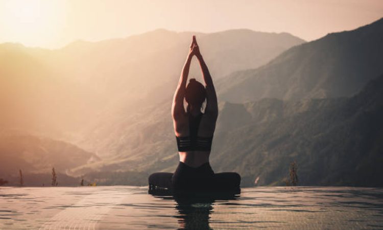 Beautiful Attractive Asian woman practice yoga Lotus pose on the pool above the Mountain peak in the morning in front of beautiful nature views,Feel so comfortable and relax in holiday,Warm tone