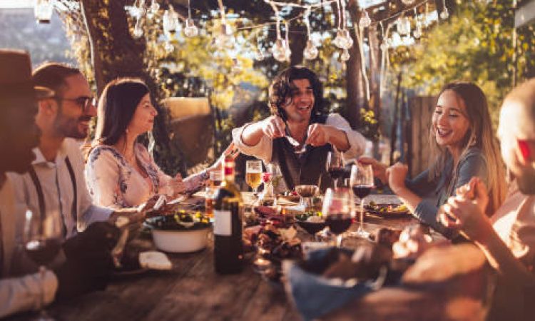 Young elegant multi-ethnic friends celebrating and having mediterranean lunch at rustic countryside mountain village house