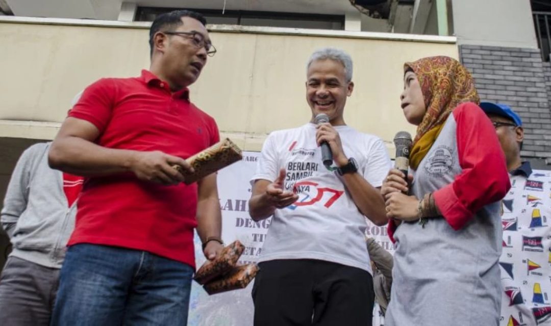 Gubernur Provinsi Jawa Barat Ridwan Kamil (kiri) bersama Gubernur Provinsi Jawa Tengah Ganjar Pranowo (tengah) memberikan hadiah kepada warga saat acara Gerakan Jawa Barat Sehat di Kawasan hari bebas kendaraan Dago, Bandung, Jawa Barat, Minggu (8/3/2020).(Foto: erakini.id)