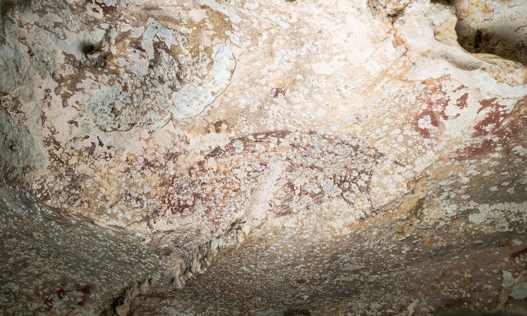 A painting created at least 51,200 years ago in the limestone cave of Leang Karampuang in the Maros-Pangkep region of the Indonesian island of Sulawesi portrays three human-like figures interacting with a wild pig, in this undated handout image. BRIN/Handout via REUTERS    THIS IMAGE HAS BEEN SUPPLIED BY A THIRD PARTY. NO RESALES. NO ARCHIVES. MANDATORY CREDIT.