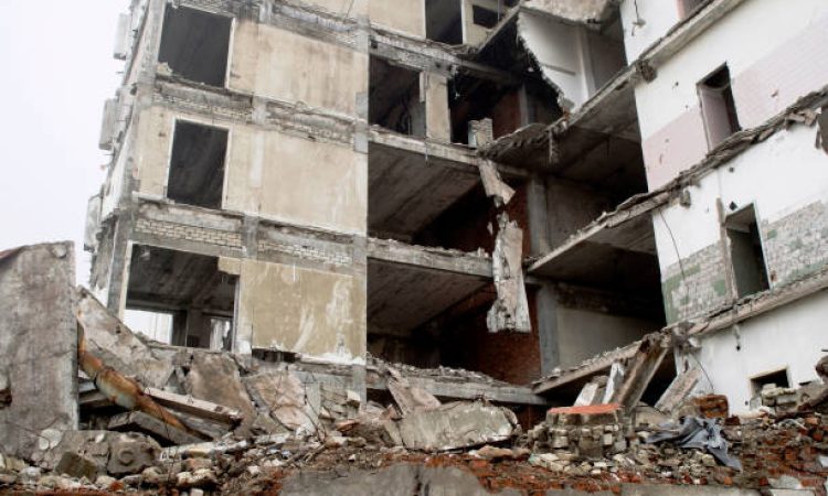 The remains of the destroyed building in the form of piles and a blockage of a pile of stones on the background of a high destroyed structure in a foggy haze. The impact of the destruction. Background