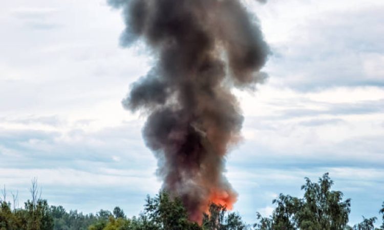 the building burns with fire and black smoke against the evening sky.