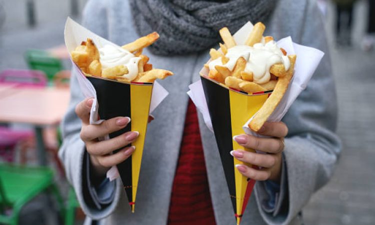 Belgian frites with mayonnaise in Brussels, Belgium. Tourist holds two portions of fries in hands in the street.