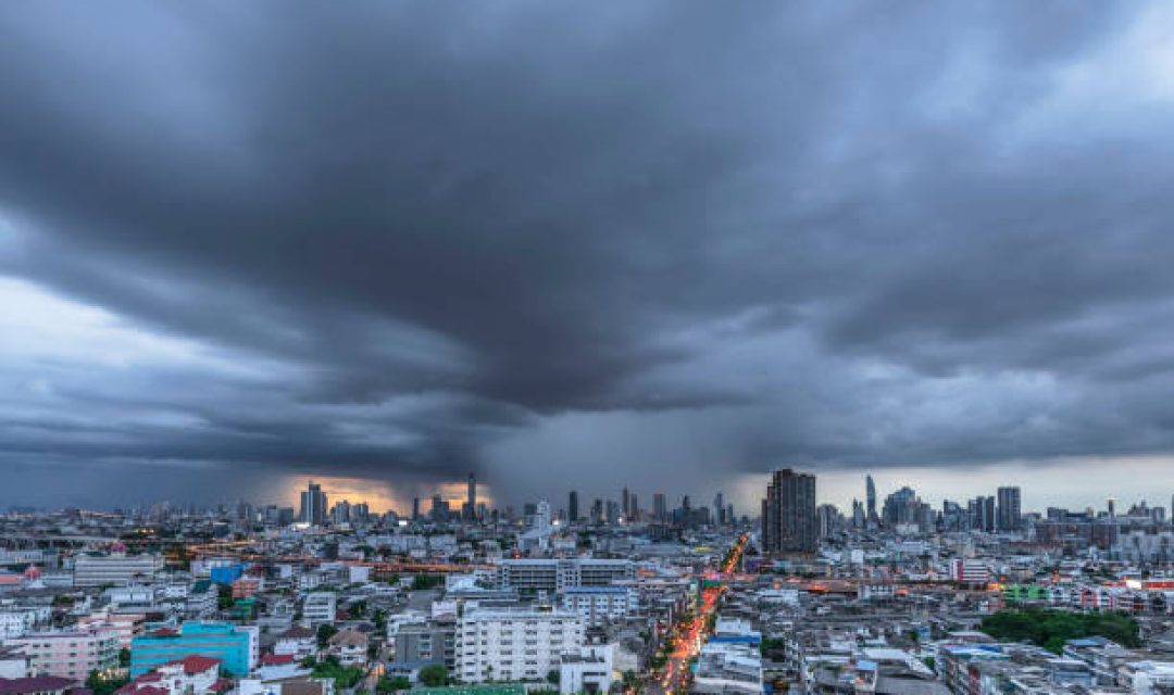 Modern city under dramatic stormy rainy clouds.