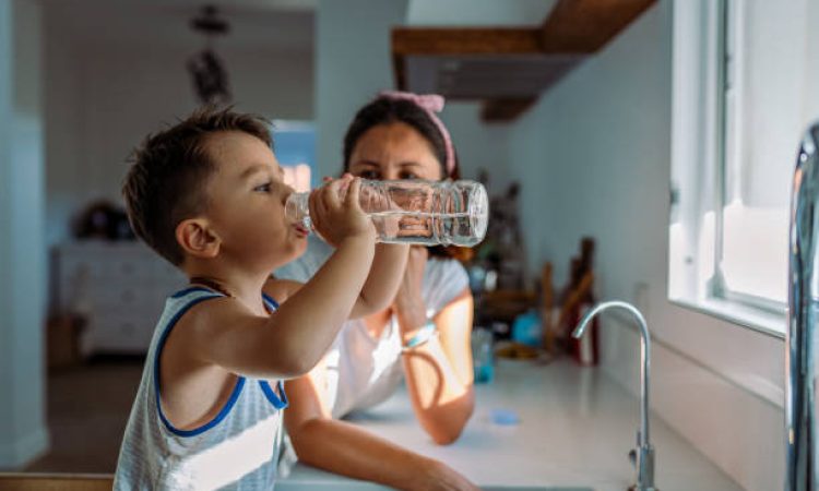 Mother and her toddler filling a glass with filtered water right from the tap