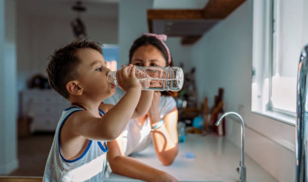 Mother and her toddler filling a glass with filtered water right from the tap