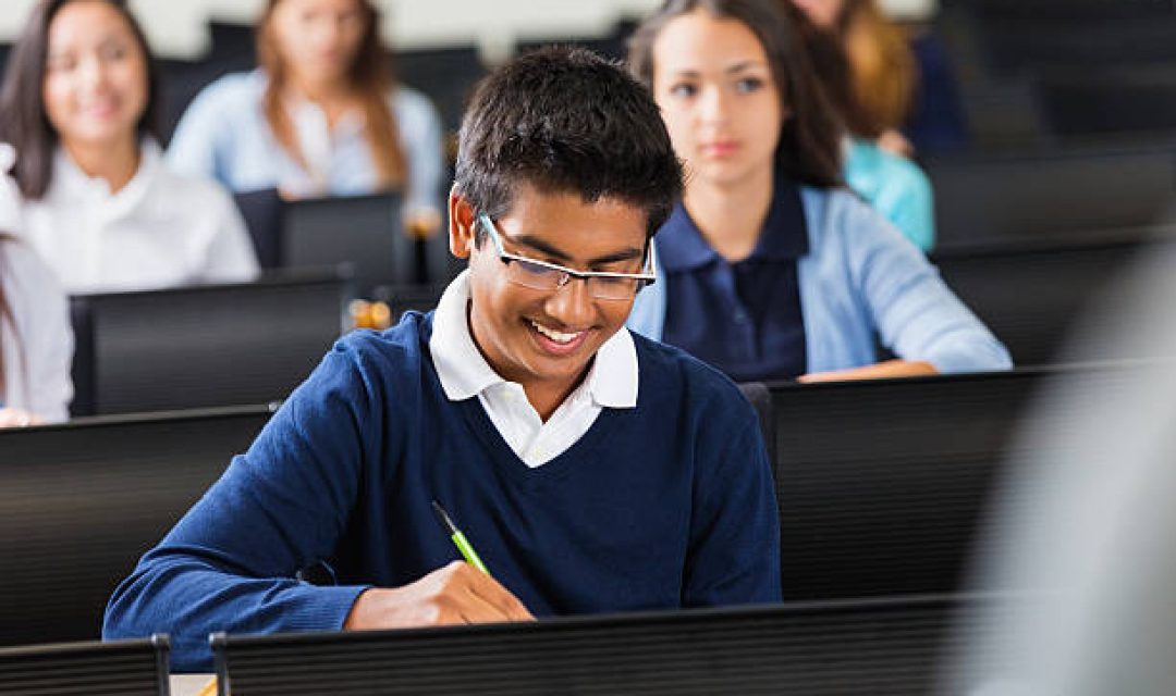 Young Indian student in private school taking notes during class